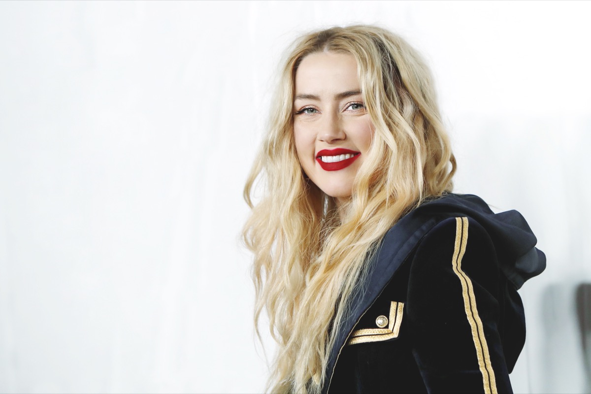 amber heard smiling while wearing black jacket and red lipstick