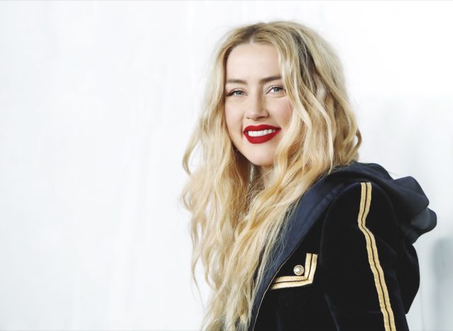 amber heard smiling while wearing black jacket and red lipstick