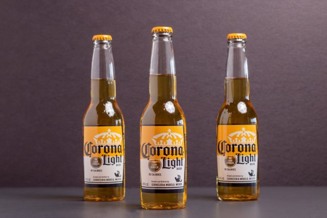 three bottles of corona light beer on gray background