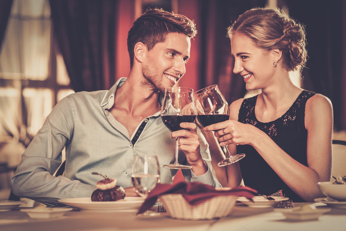 Beautiful young couple with glasses of red wine in luxury restaurant