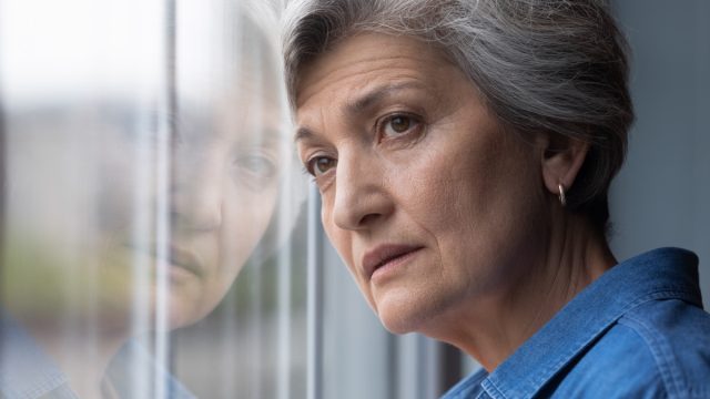 Anciana canosa con la cabeza mirando hacia la ventana