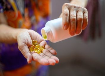 Bottle of omega 3 fish oil capsules pouring into hand.