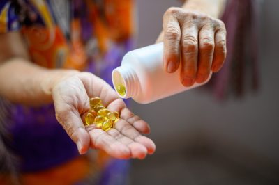 Bottle of omega 3 fish oil capsules pouring into hand.