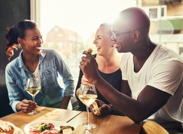 group of multiethnic friends in their 30s drinking wine outside at a table