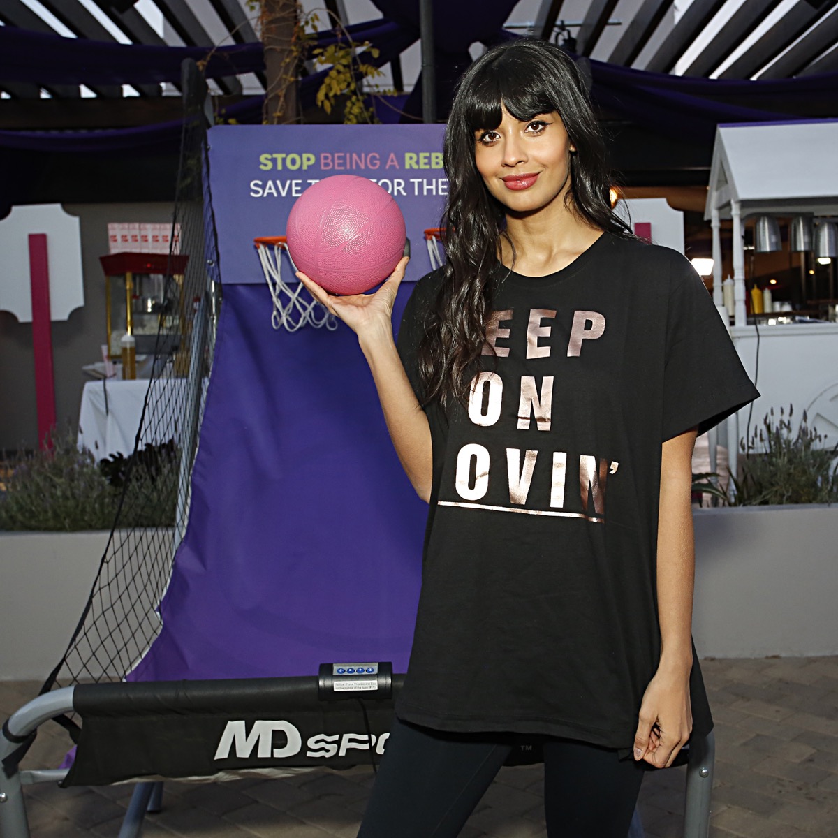 jameela jamil in black t-shirt holding pink basketball