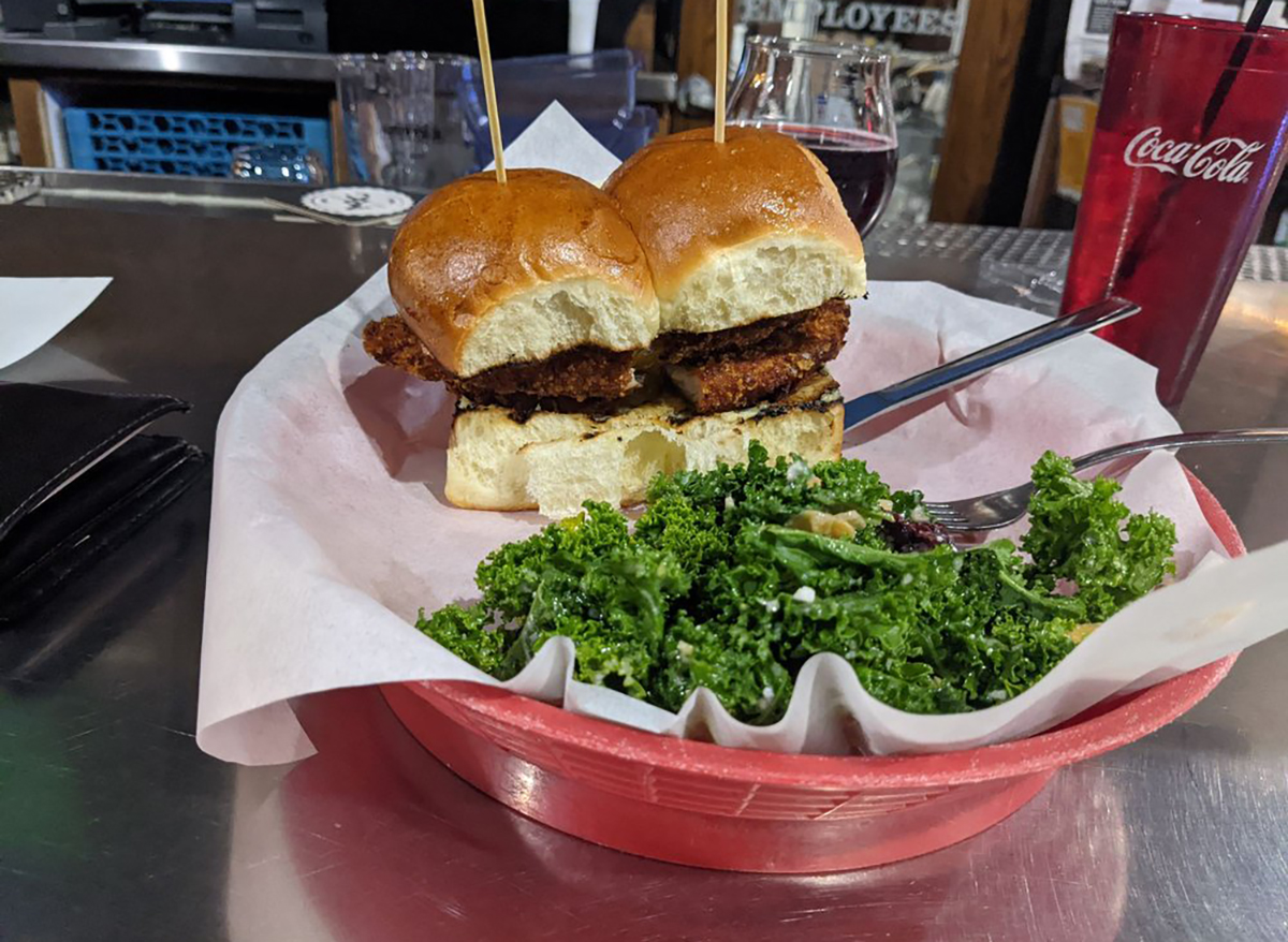 chicken sandwich and kale salad on table