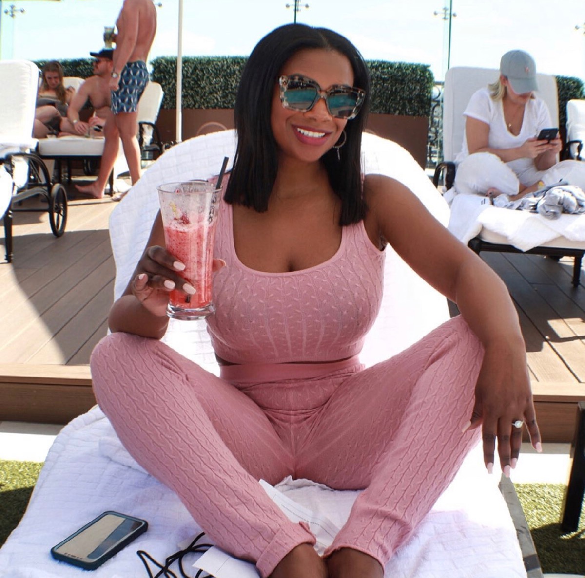 kandi burruss sitting outside drinking pink smoothie in an all-pink outfit