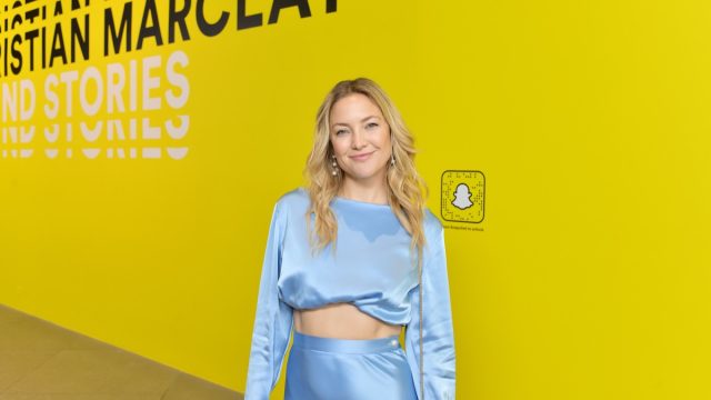 kate hudson in two-piece satin outfit in front of yellow snapchat step-and-repeat