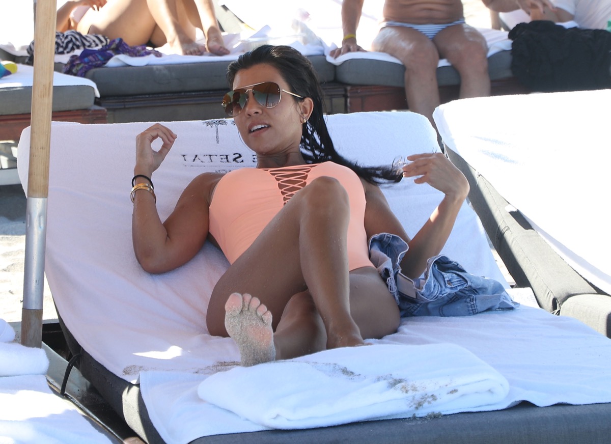 kourtney kardashian in pink swimsuit on lounge chair