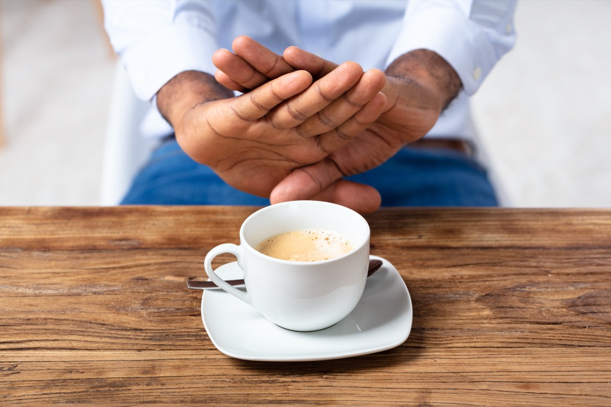 picture of man putting two hands out to refuse a cup of coffee
