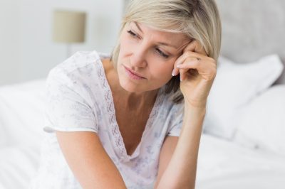 Mature woman sitting in bed at home.