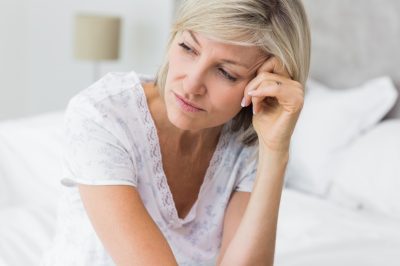 Mature woman sitting in bed at home.