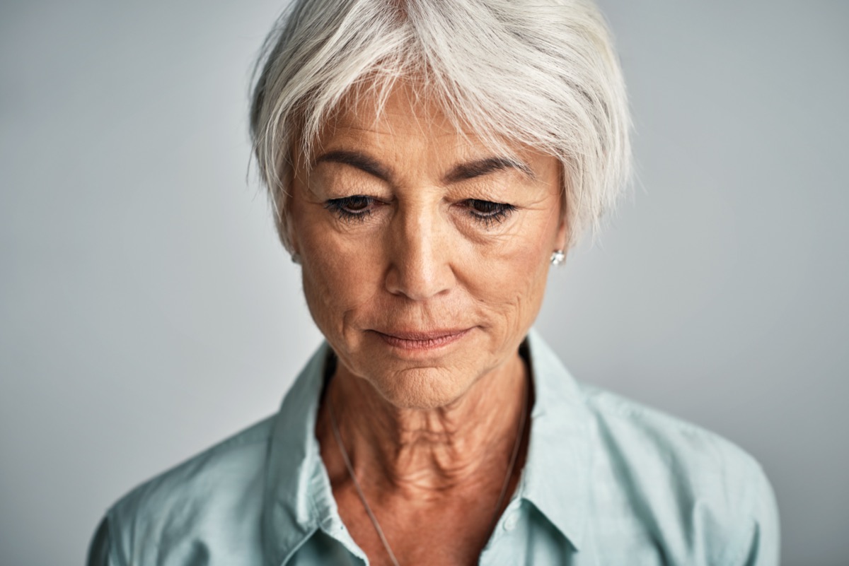 Senior woman posing against a grey background.