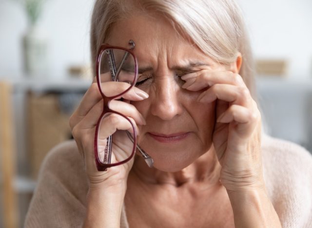 Mature woman takes off her glasses and massages eyes.