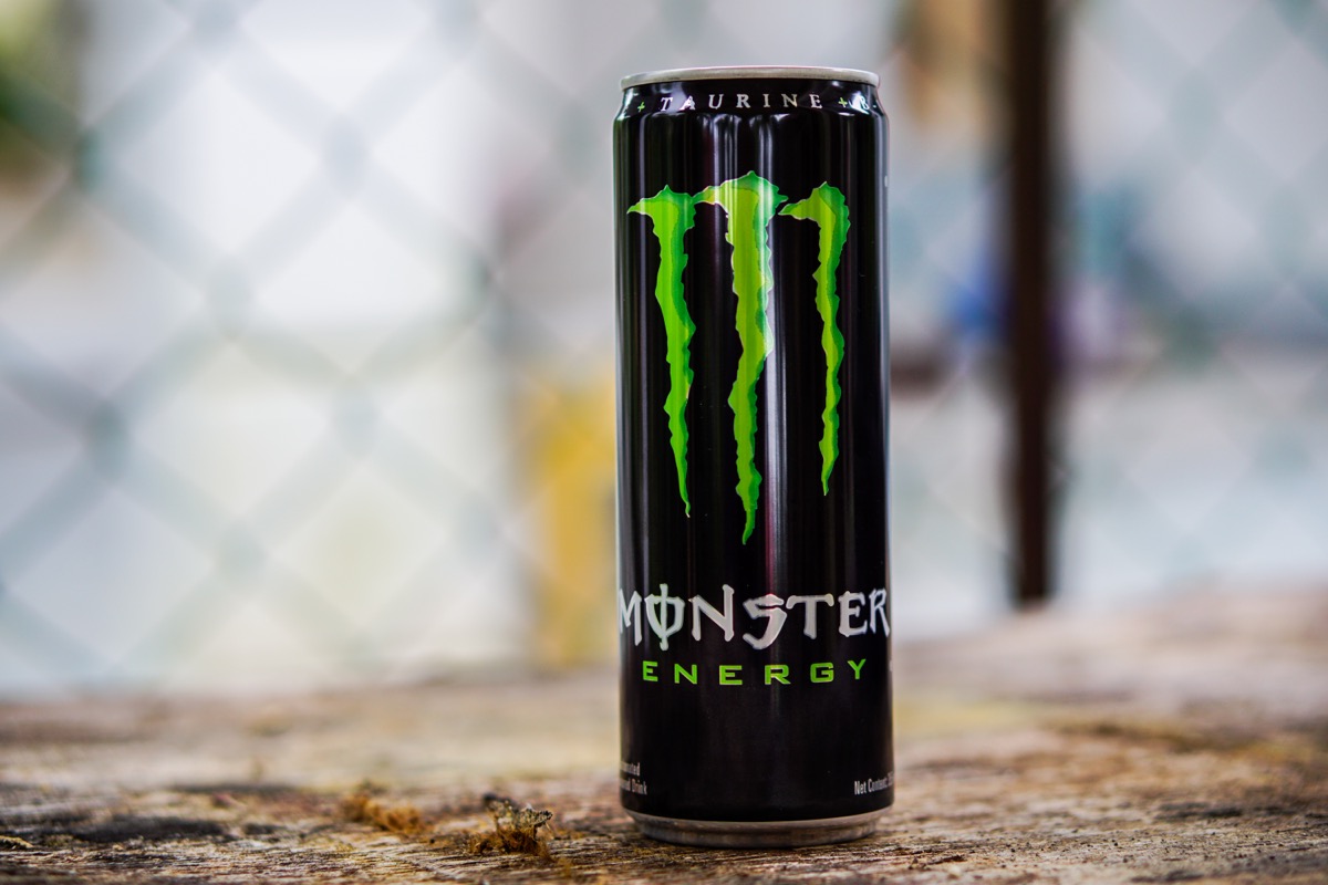 can of monster energy drink in front of chain link fence