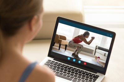 Focus on laptop screen with young woman in sportswear doing morning exercises, deep squats on yoga mat, staying fit at home. Interested girl watching online educational fitness workshop training. on laptop screen with young woman in sportswear doing morning exercises, deep squats on yoga mat, staying fit at home. Interested girl watching online educational fitness workshop training.