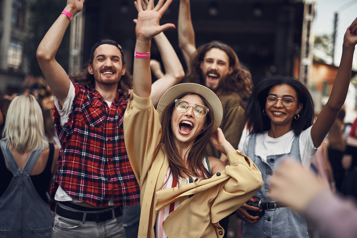 Our favorite song. Waist up portrait of young stylish people raising hands and smiling