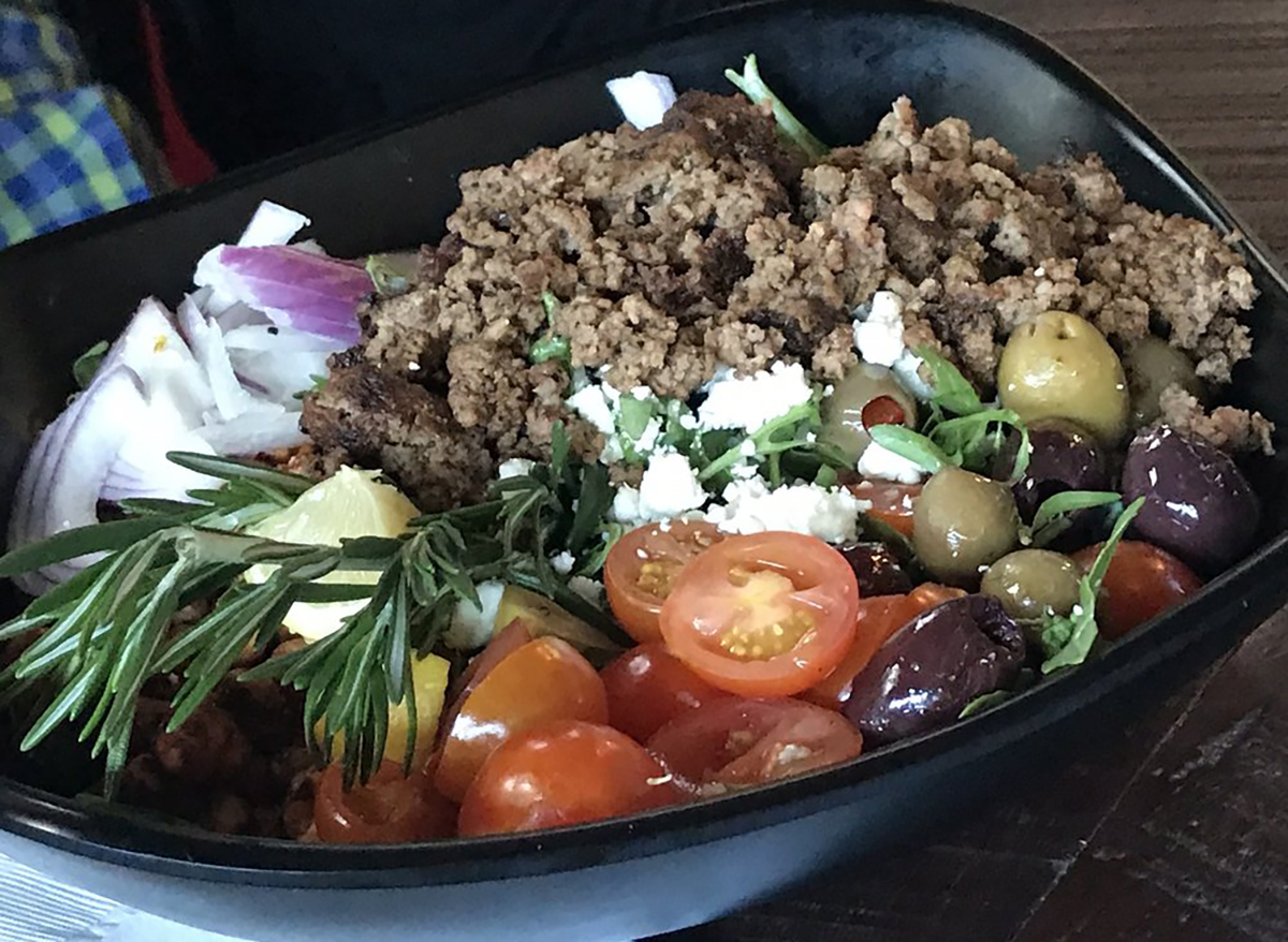 salad topped with rosemary sprigs tomatoes and ground beef