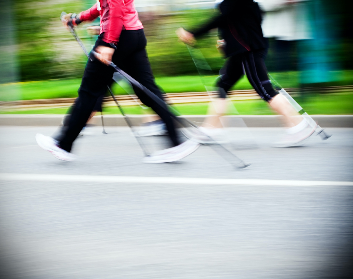 Woman nordic walking race on city streets. Walkers in marathon competition running fast