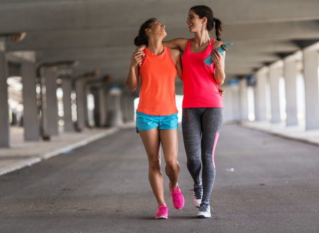 Couple of female friends jogging on the city street under the city road overpass.They relaxing after jogging and making fun.Embracing each other. Walkers