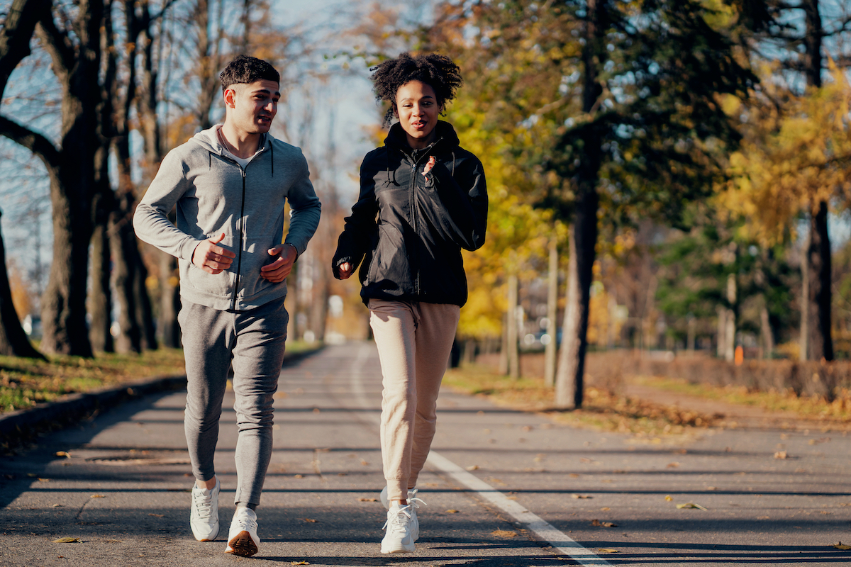 Sports couple in the park in the morning. They are engaged in long-distance running. Heart training cardio system in the fresh air, useful for blood vessels. Comfortable sportswear.