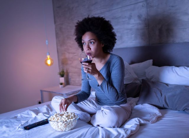 woman eating popcorn and drinking wine watching movie