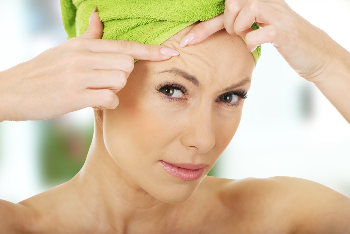 Beauty woman checking wrinkles on her forehead, closeup