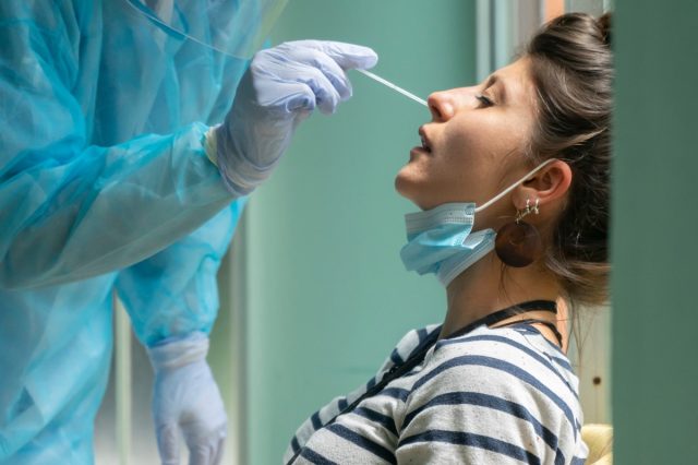 A healthcare worker with protective gear takes a coronavirus swab from a woman.