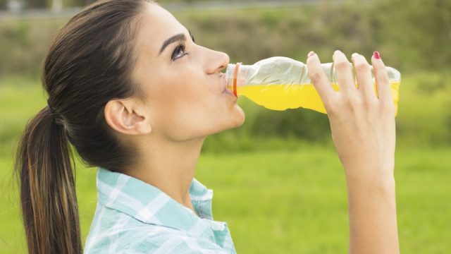 Woman drinking juice from a bottle outdoor