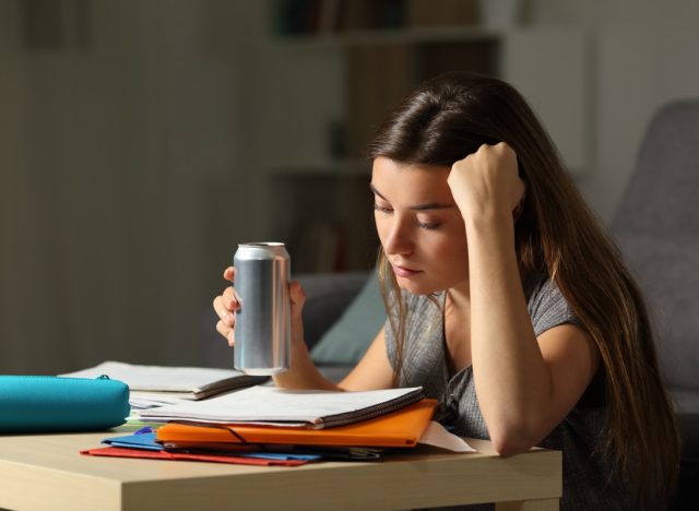 young woman drinking energy drink while studying