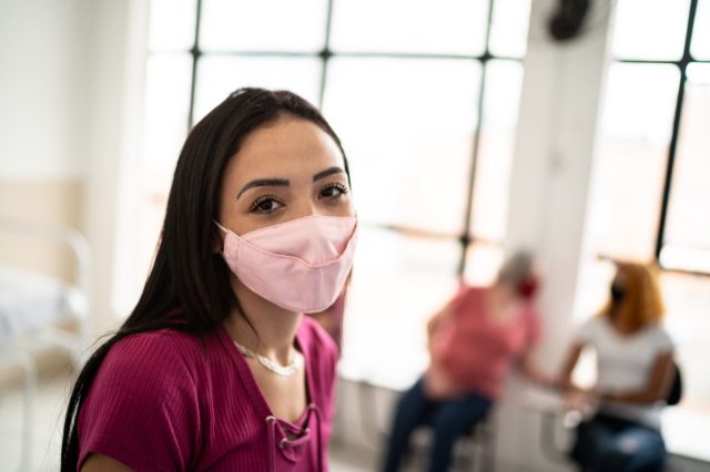 woman in a hospital waiting room - wearing a face mask