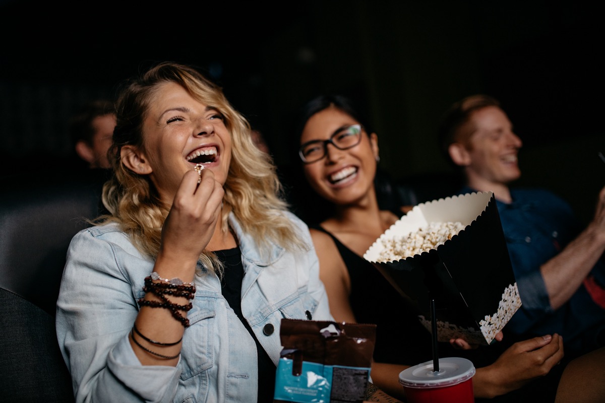 Woman with friends watching movie in cinema and laughing.