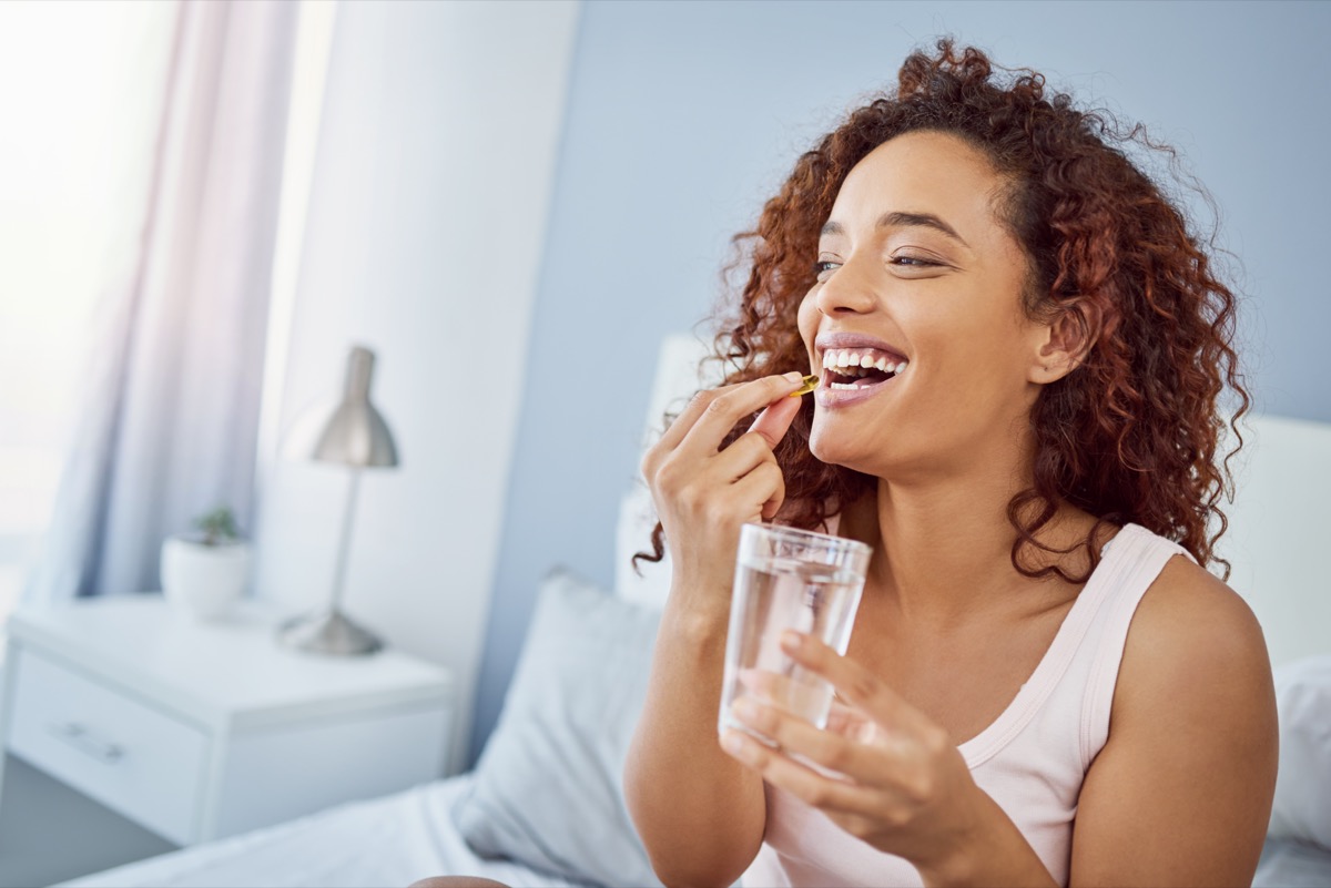 Woman taking her medication in her bedroom at home.