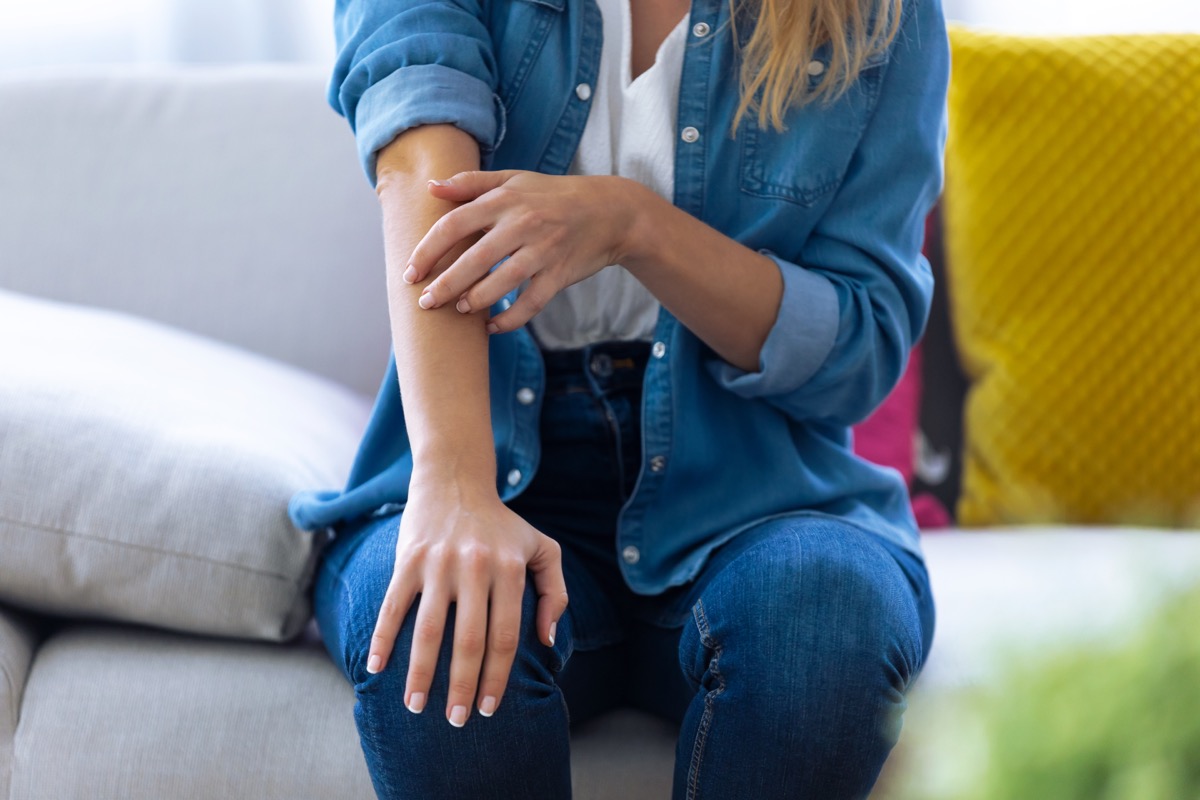 woman in jean jacket and pants itching arm