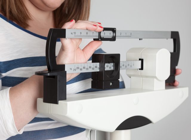 overweight woman weighing herself on scale