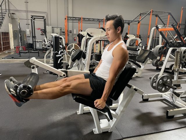 trainer performing leg extensions