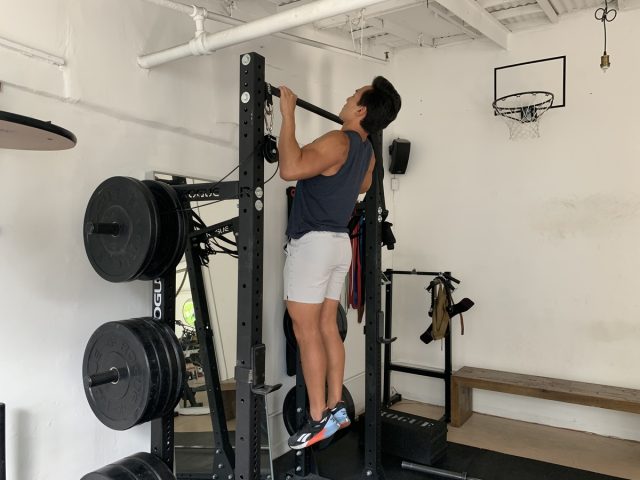 trainer performing chin-up exercise to get rid of back fat