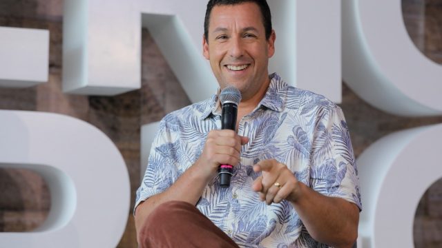 adam sandler holding microphone and laughing