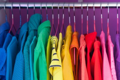 Colored clothing of all colors of the rainbow / spectrum hanging in the wardrobe.