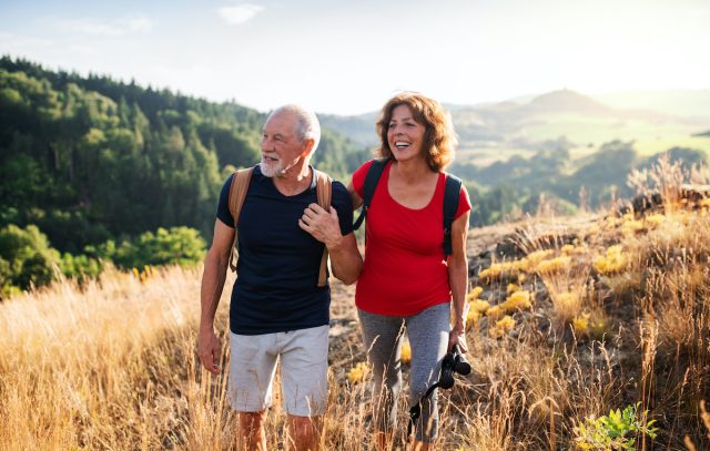 Senior tourist couple travellers hiking in nature, walking and talking.