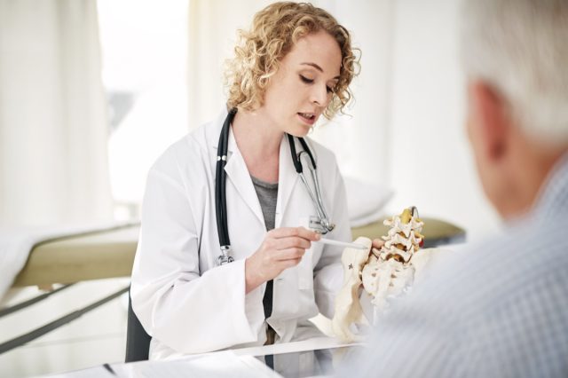 Shot of a doctor explaining a medical procedure with a model to a senior patient while sitting in her office