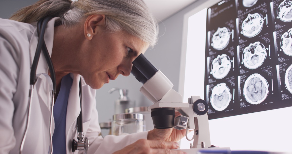 Un neurologue d'âge moyen regardant avec un microscope