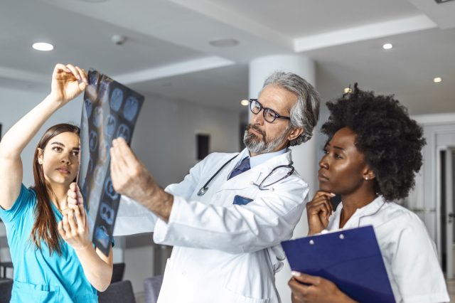 Team of healthcare professionals looking x-ray of the patient's lungs.