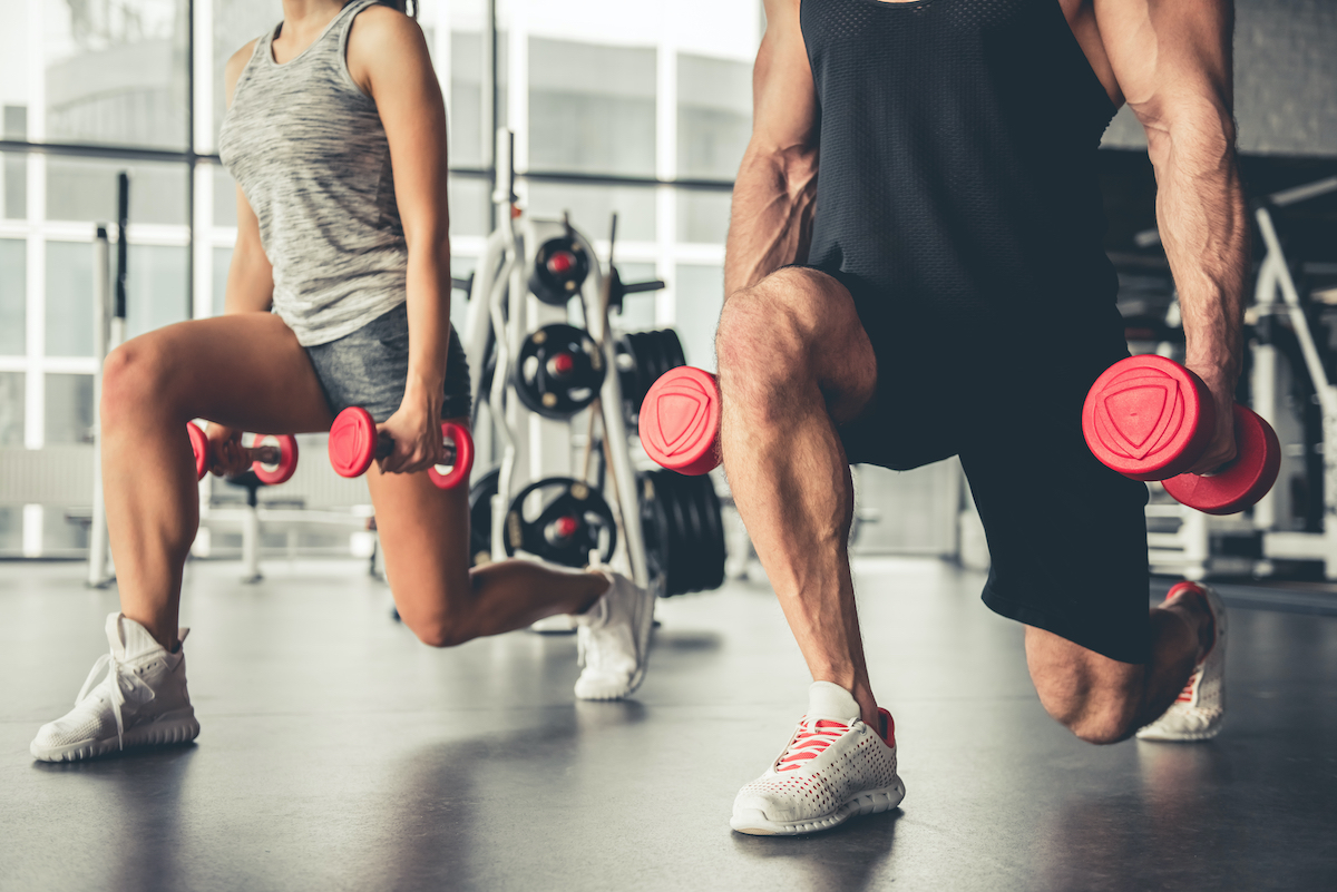 Attractive sports people are working out with dumbbells in gym