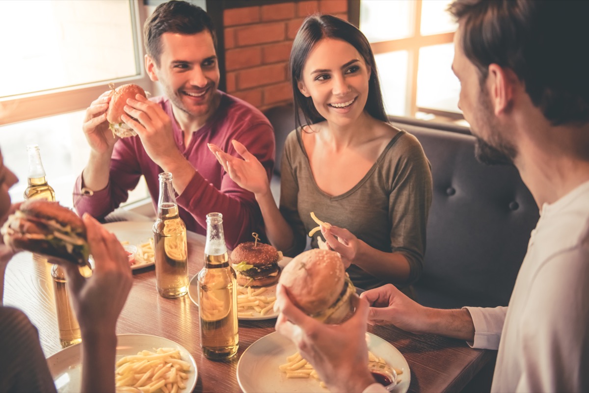 friends eating burgers in restaurant