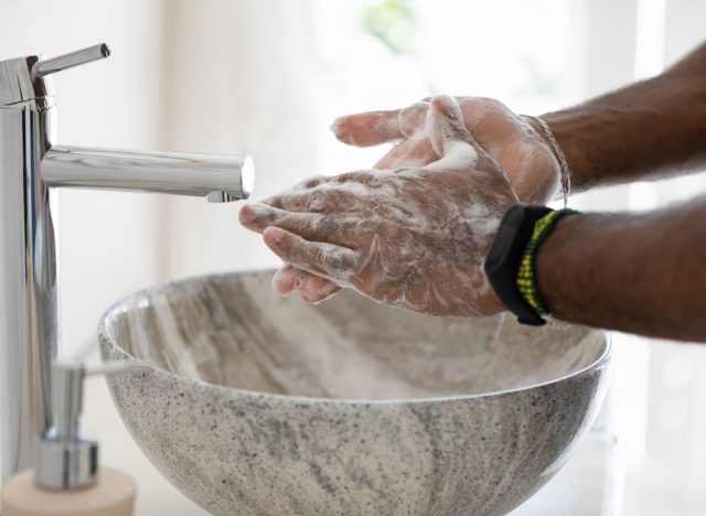 person washing hands in modern marble bowl sink