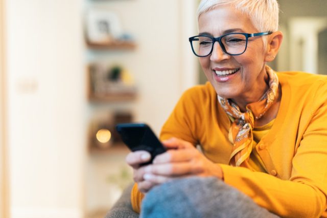 Modern mature woman texting at home