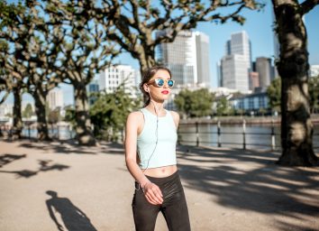 Young woman in sportswear having a morning exercise walking in the park with skyscrapers on the background in Frankfurt city