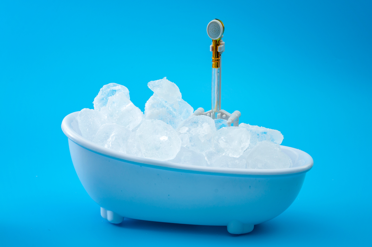 Muscle recovery and healing therapy, performance improvement treatment and extreme cold cryotherapy concept with minimalist bathtub filled with ice isolated on blue background