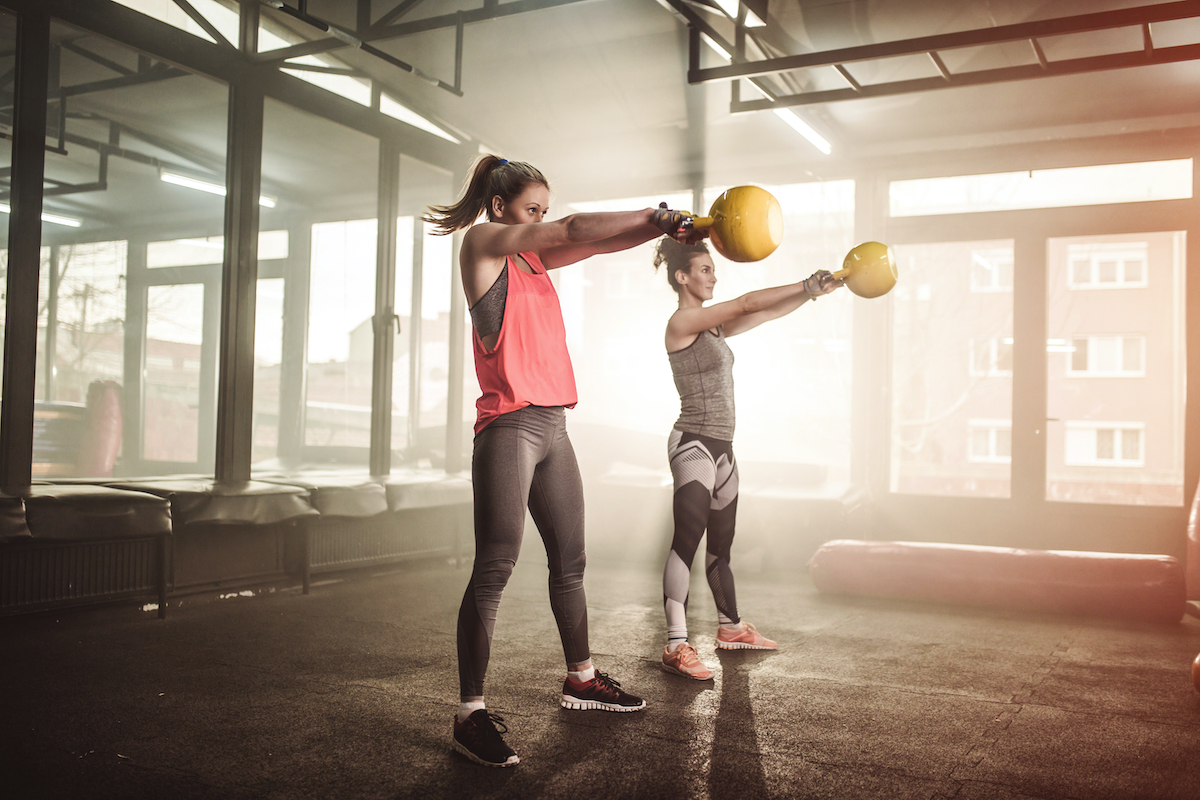 Two woman lifting kettle bell in cross fit gym